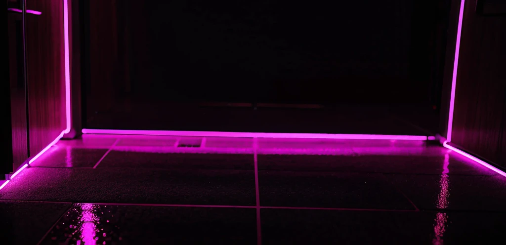 party neon sign in black background, with reflections on the floor.
