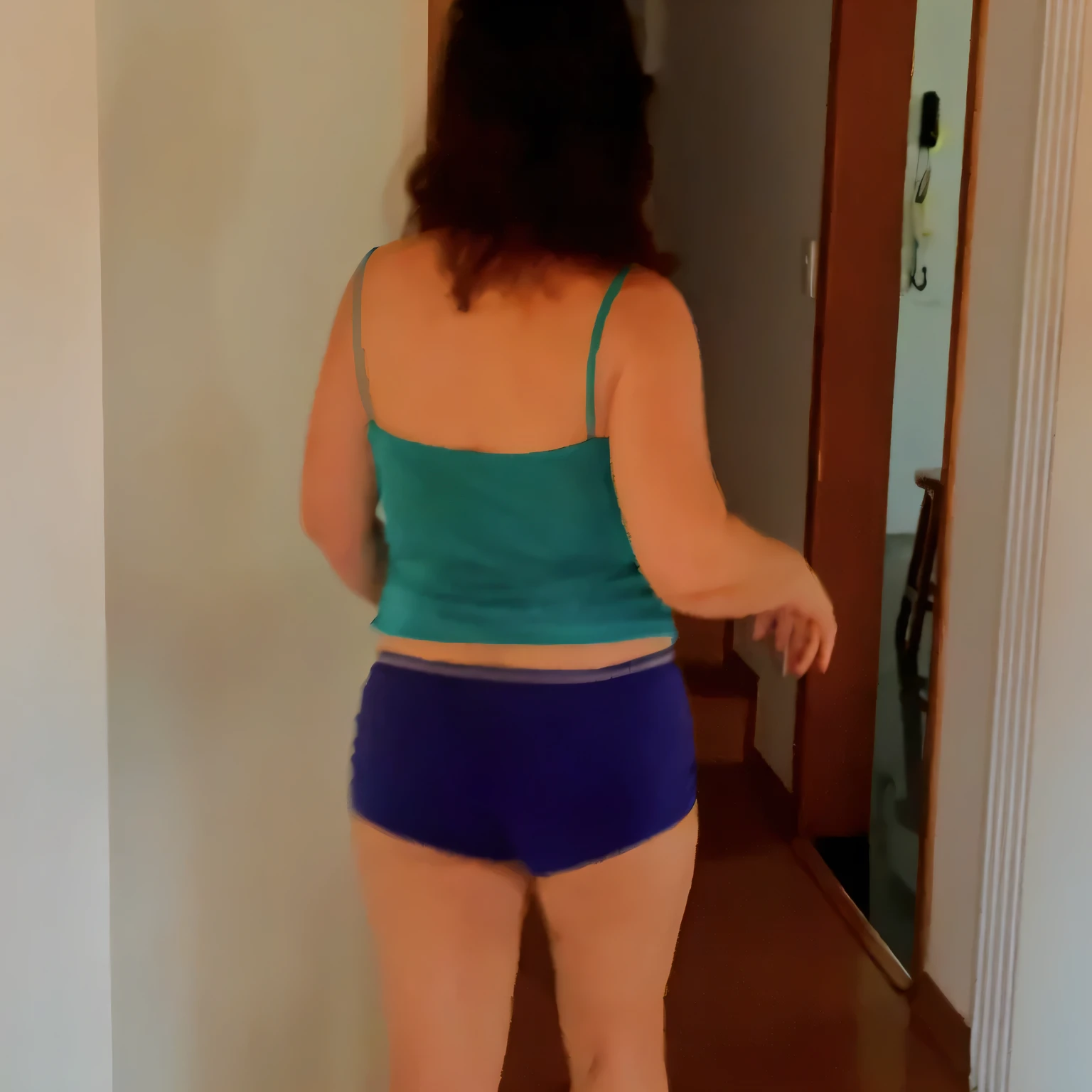 there is a woman in a blue top and blue shorts standing in a hallway, seen from the back, view from the back, in shorts, wearing a camisole and shorts, seen from behind, photographed from the back, shapely derriere, blue undergarments, shot from the back, sport bra and dark blue shorts, photo still of posterior view