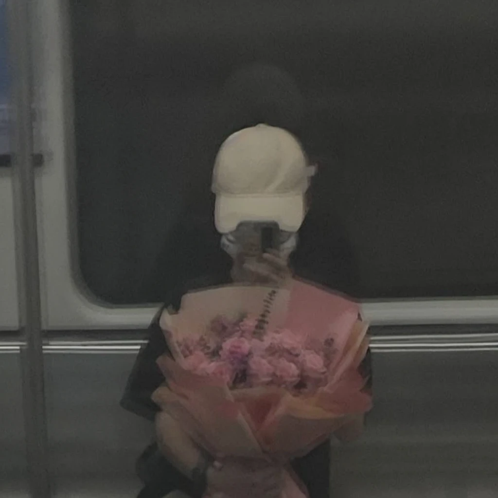 Prompt:

"Reflection of a person on a subway window, holding a bouquet of pink flowers. The person is wearing a white cap and a black outfit, partially obscured by the reflection and dim lighting. The background shows a blurred, dark subway interior, giving a moody and introspective ambiance. The bouquet is wrapped in pink paper, adding a soft, delicate contrast to the otherwise dark and muted tones of the scene."

Detailed Breakdown:

Setting: Subway window with reflection, dark interior.
Subject: Person holding a bouquet, wearing a white cap and black outfit.
Lighting: Dim, moody, emphasizing the reflective surface.
Colors: Dark tones with a pop of pink from the flowers.
Mood: Introspective, calm, and somewhat melancholic.
Use these details to guide the stable diffusion model in creating an image with a similar vibe and composition.