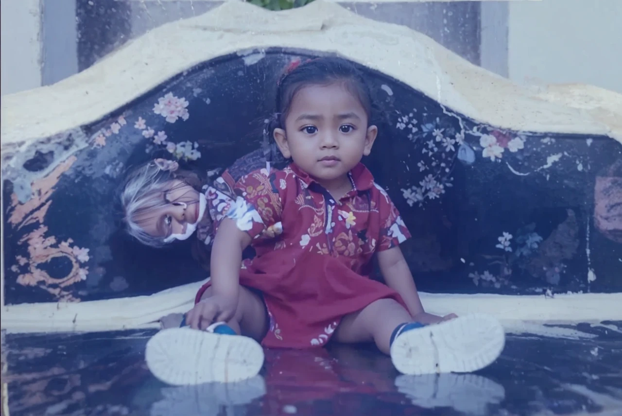 Karikatur keluarga kecil Indonesia, di depan teras rumah sederhana, pakaian seragam memakai batik, di rumah khas Madura, ayah berumur 45 tahun bercelana memakai peci hitam, ibu berumur 35 tahun memakai hijab, dan 2 anak laki-laki berumur 16 tahun dan 12 tahun, 3 anak perempuan berumur 7 tahun, 3 tahun dan 2 tahun realistis, cinematic, 3D. HD