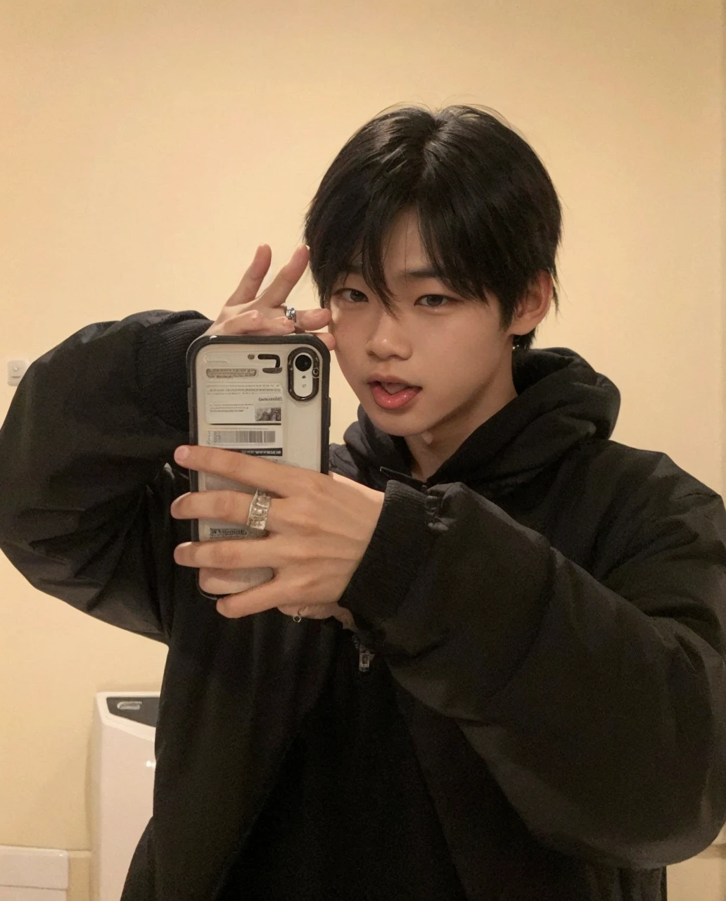 An Asian boy showing his tongue and holding his cell phone