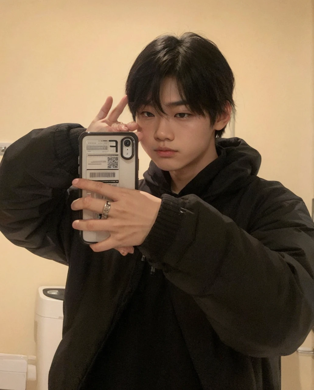 Asian boy pouting, with one hand close to his face and the other not holding his cell