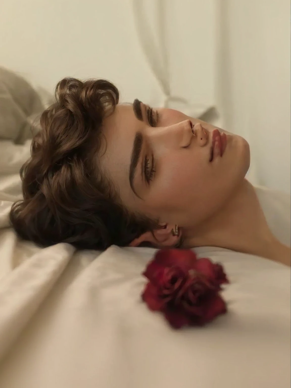 Hay un hombre acostado en una cama con una rosa., beautiful androgynous prince, cara perfecta y chico, Timothée Chalamet, delicate androgynous prince, tendido sobre rosas, portrait of Timothée Chalamet, por Irakli Nadar, he has short curly brown hair, por Anna Haifisch, handsome young prince, Aesthetic Portrait
