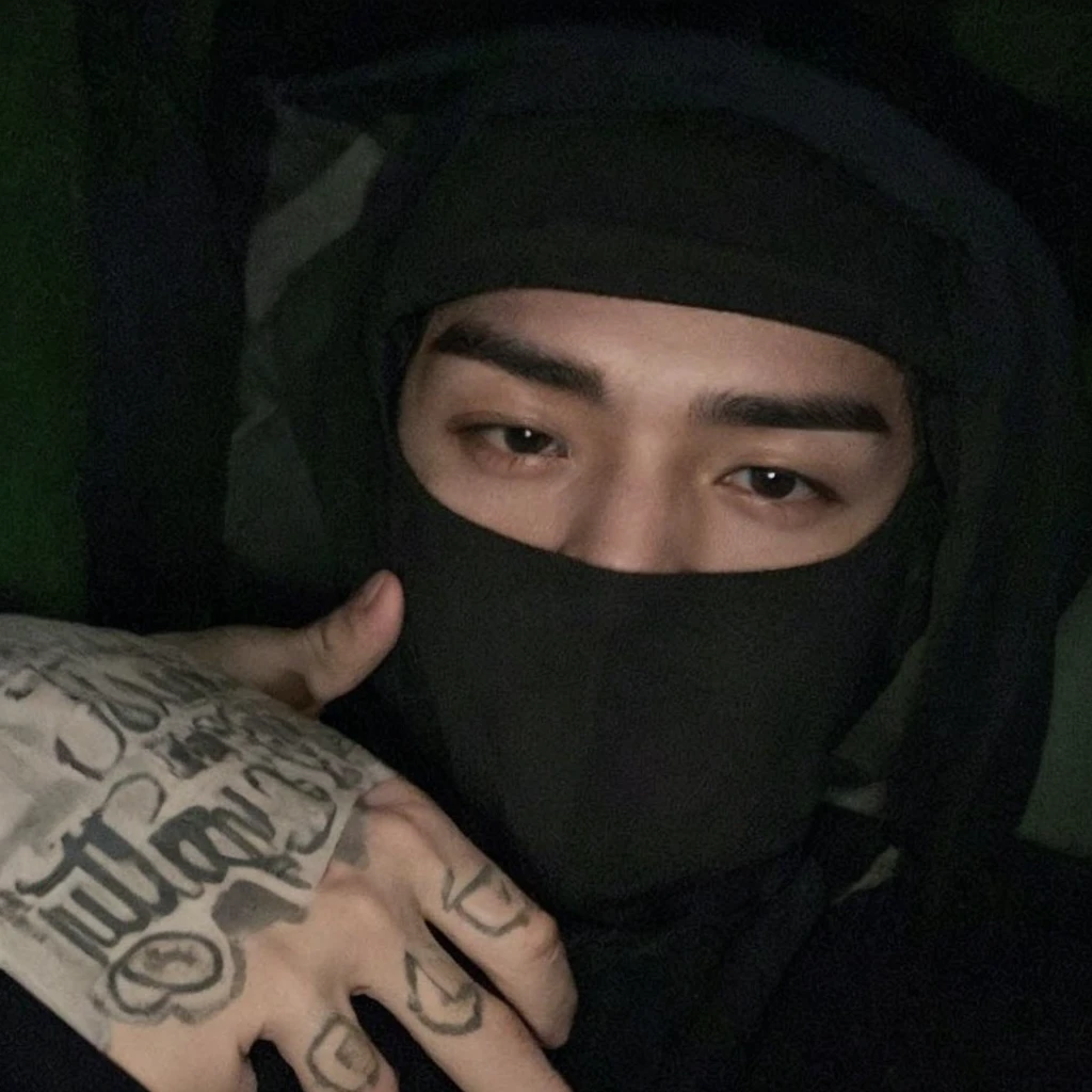 Korean boy, prominent feature of his face, enhancing his unique and captivating appearance, thick eyebrows, colored, pale skin with hair falling on his forehead, wearing a balaclava highlighting the color of his eyes and wearing a low-cut shirt, showing his musculature, he is sitting on a sofa making a sign with one of his hands and his body is toned like that of a Russian military man.