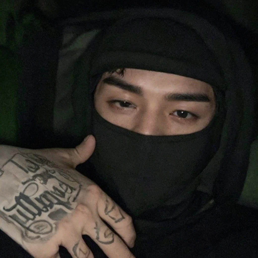Korean boy, prominent feature of his face, enhancing his unique and captivating appearance, thick eyebrows, colored, pale skin with hair falling on his forehead, wearing a balaclava highlighting the color of his eyes and wearing a low-cut shirt, showing his musculature, he is sitting on a sofa making a sign with one of his hands and his body is toned like that of a Russian military man.