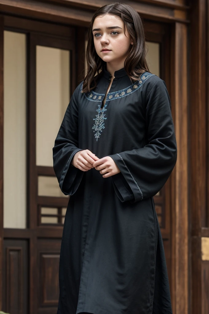 Beautiful brunette girl identical to Maisie Williams in a long black tunic with blue embroidery 