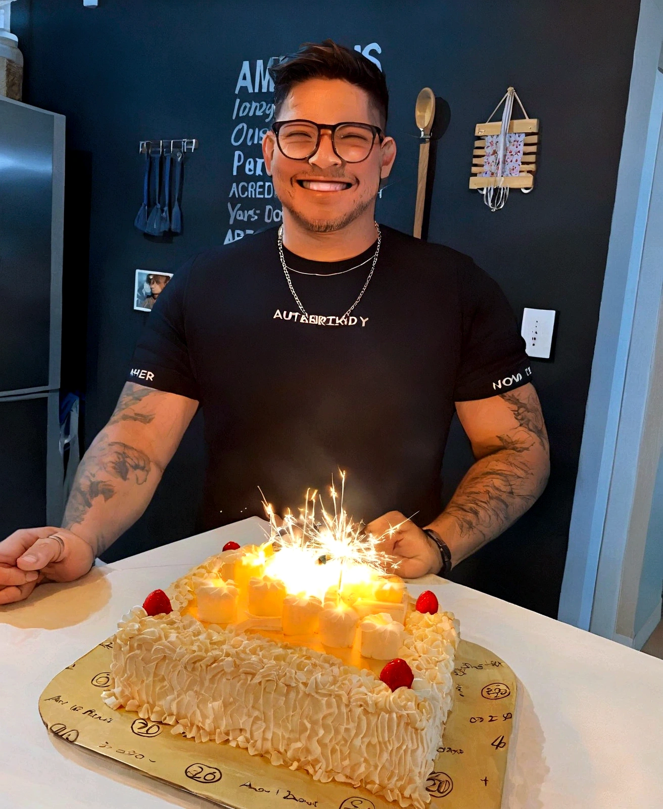 smiling man in glasses holding a birthday cake lit with candles, he is! about 30 years, he is about 30 years old, he is about 30 years, he is about 4 0 years old, he is about 40 years old, 29-years-old, 27 years old, he is about 2 5 years old, celebrating a birthday