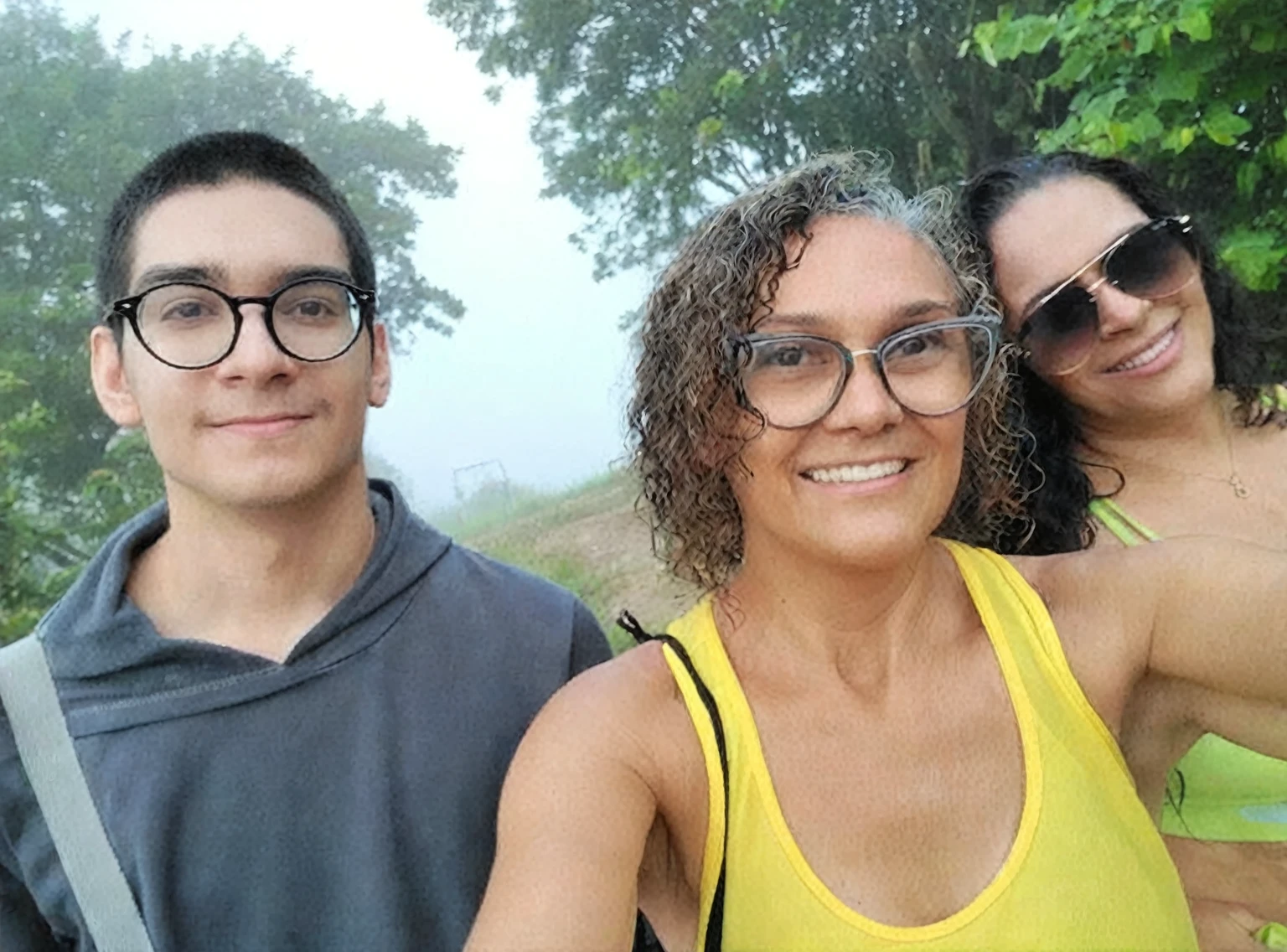 there are three people taking a selfie together in the forest, fog in background, antique photo, vhs, worn photo, noise.