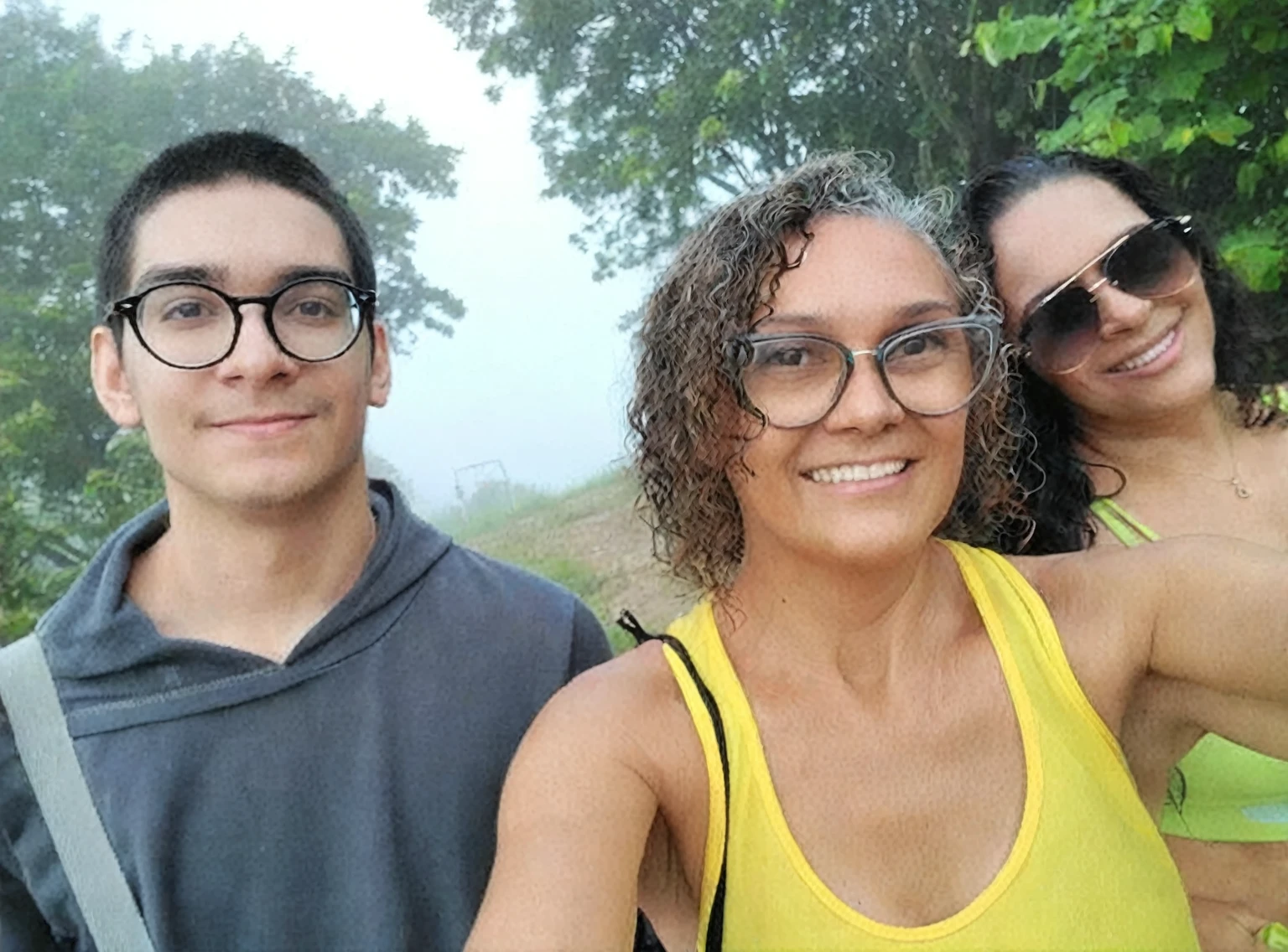 there are three people taking a selfie together in the forest, fog in background, antique photo, vhs, worn photo, noise.