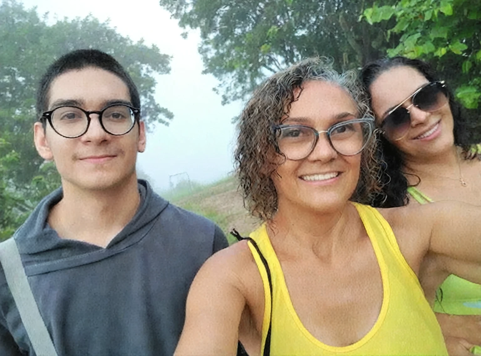 there are three people taking a selfie together in the forest, fog in background, antique photo, vhs, worn photo, noise.