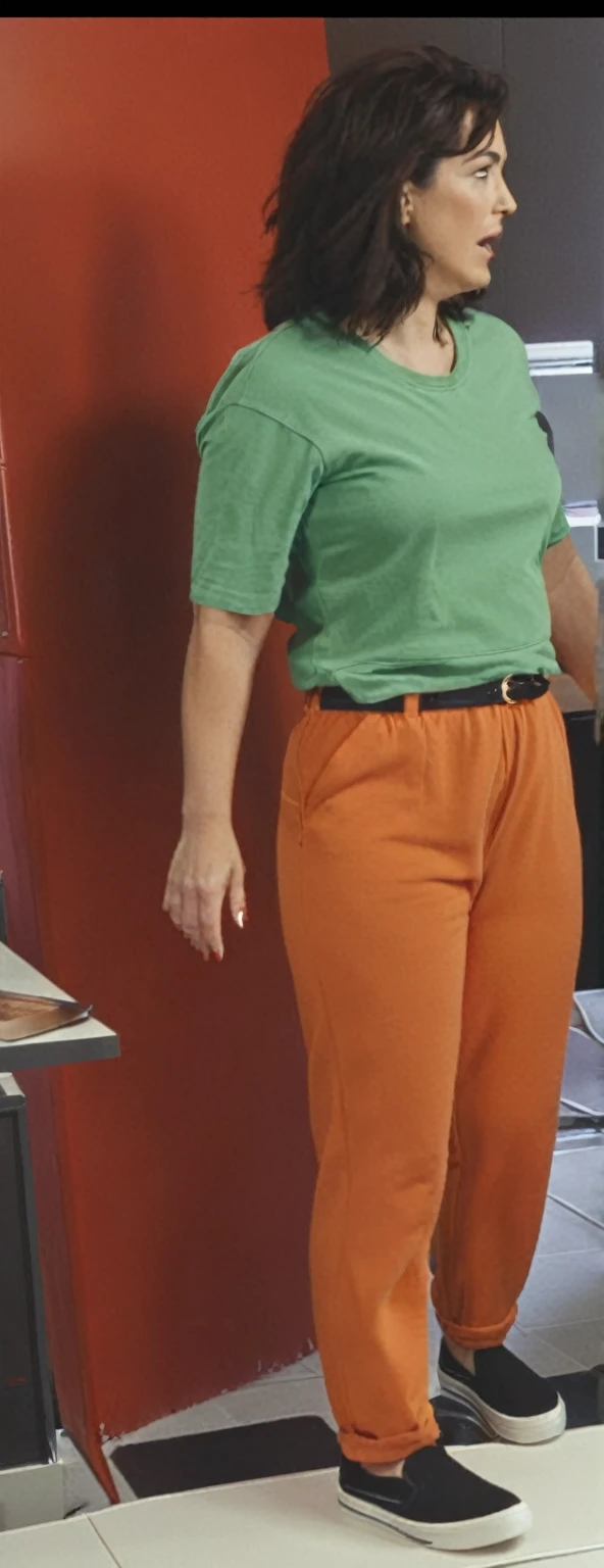 there is a woman standing in front of a computer screen, red shirt brown pants, wearing an orange t-shirt, wearing an orange t shirt, wearing pants and a t-shirt, middle shot waist up, wearing pants, wearing an orange jumpsuit, wearing orange prison jumpsuit, orange fluffy belly, vibrant but dreary orange, hand on hips, large pants
