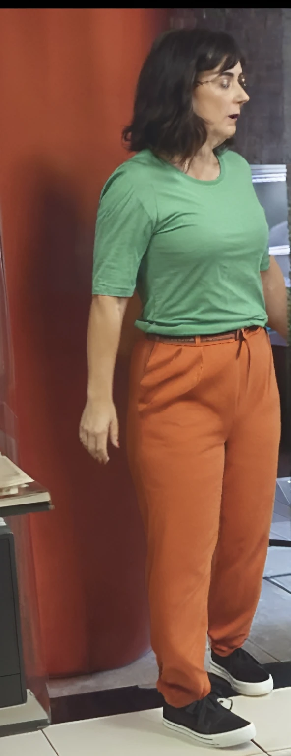 there is a woman standing in front of a computer screen, red shirt brown pants, wearing an orange t-shirt, wearing an orange t shirt, wearing pants and a t-shirt, middle shot waist up, wearing pants, wearing an orange jumpsuit, wearing orange prison jumpsuit, orange fluffy belly, vibrant but dreary orange, hand on hips, large pants