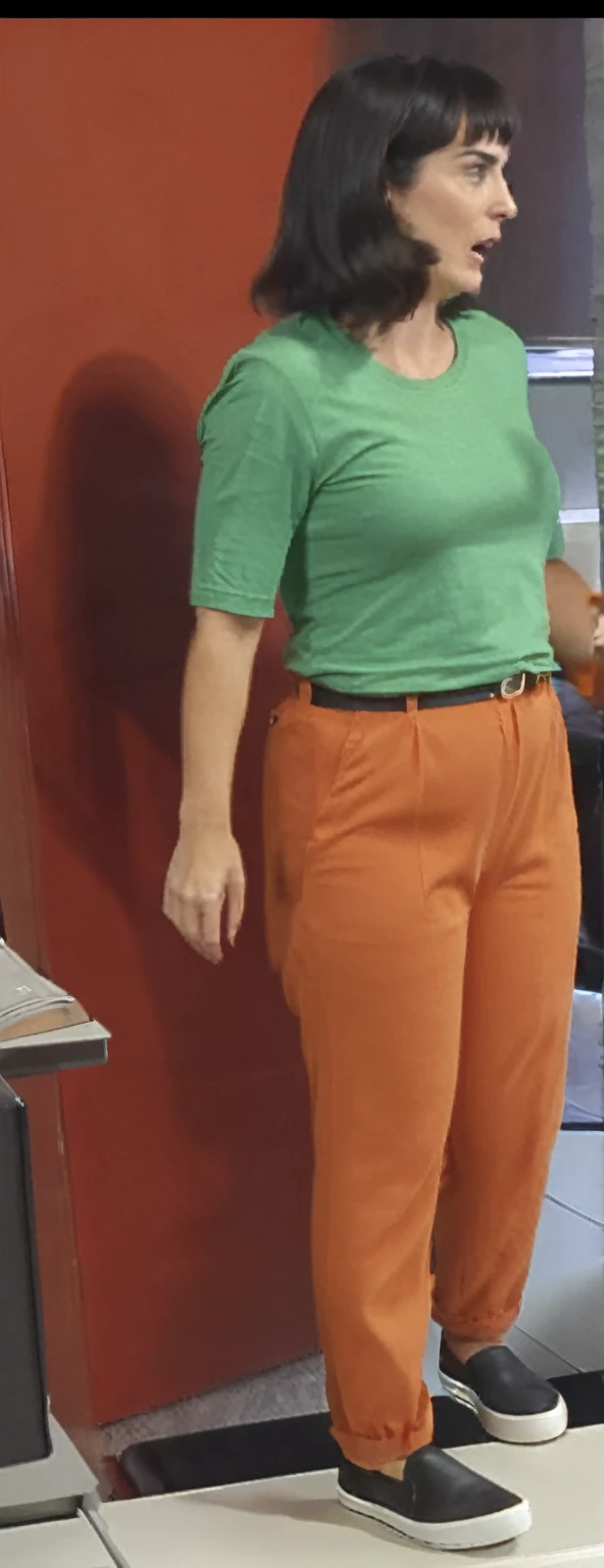 there is a woman standing in front of a computer screen, red shirt brown pants, wearing an orange t-shirt, wearing an orange t shirt, wearing pants and a t-shirt, middle shot waist up, wearing pants, wearing an orange jumpsuit, wearing orange prison jumpsuit, orange fluffy belly, vibrant but dreary orange, hand on hips, large pants