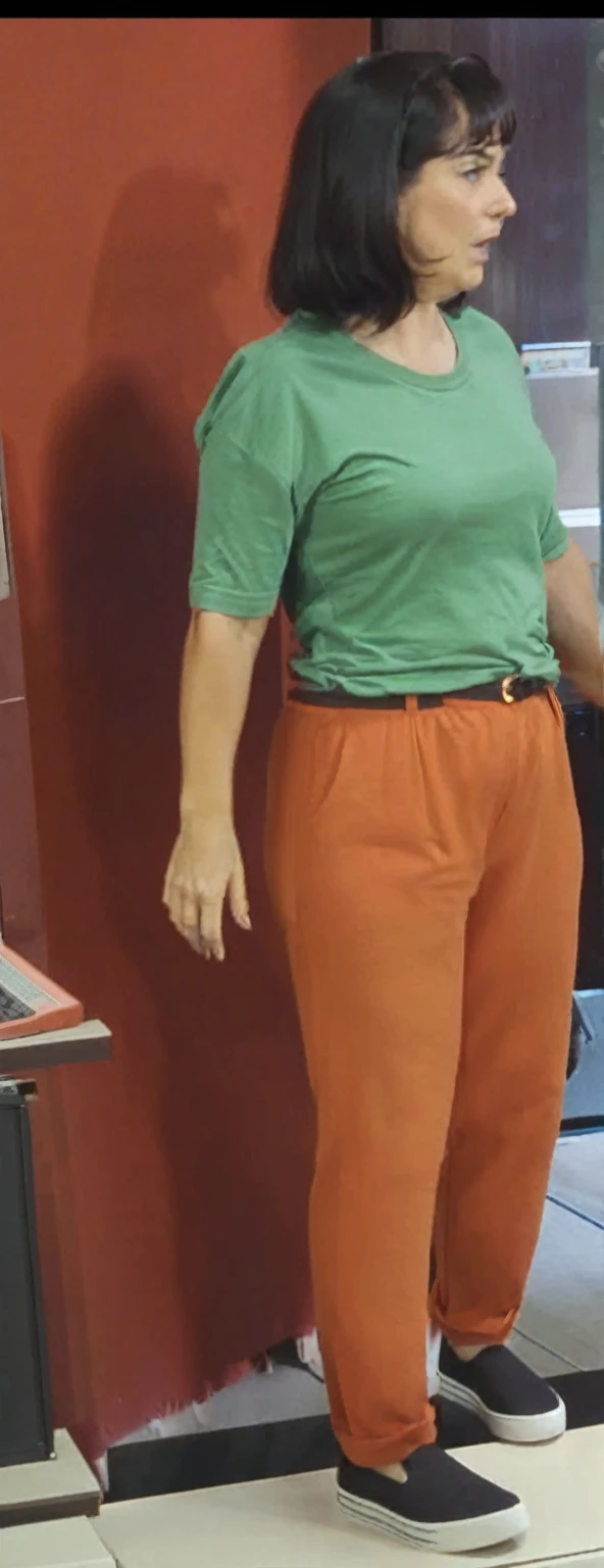 there is a woman standing in front of a computer screen, red shirt brown pants, wearing an orange t-shirt, wearing an orange t shirt, wearing pants and a t-shirt, middle shot waist up, wearing pants, wearing an orange jumpsuit, wearing orange prison jumpsuit, orange fluffy belly, vibrant but dreary orange, hand on hips, large pants