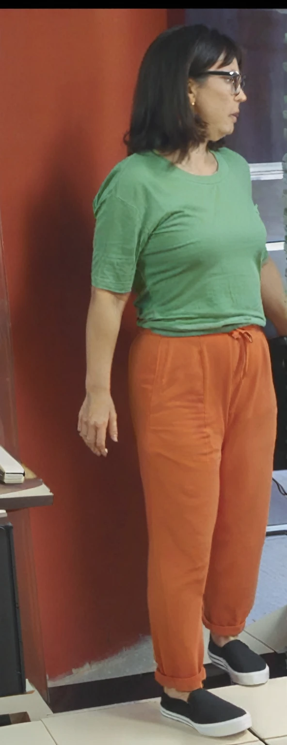 there is a woman standing in front of a computer screen, red shirt brown pants, wearing an orange t-shirt, wearing an orange t shirt, wearing pants and a t-shirt, middle shot waist up, wearing pants, wearing an orange jumpsuit, wearing orange prison jumpsuit, orange fluffy belly, vibrant but dreary orange, hand on hips, large pants