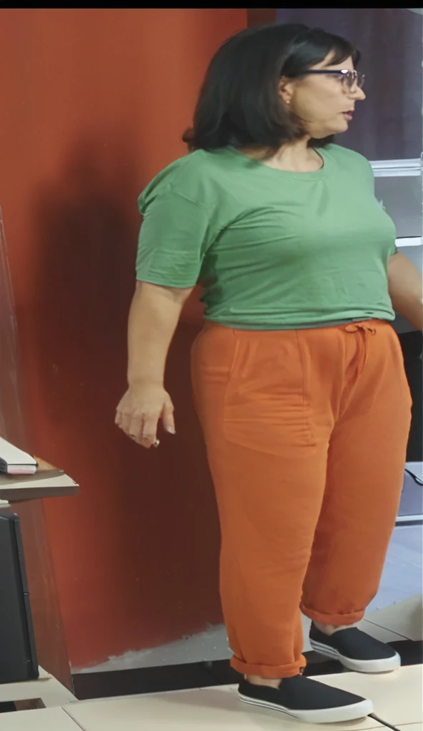 there is a woman standing in front of a computer screen, red shirt brown pants, wearing an orange t-shirt, wearing an orange t shirt, wearing pants and a t-shirt, middle shot waist up, wearing pants, wearing an orange jumpsuit, wearing orange prison jumpsuit, orange fluffy belly, vibrant but dreary orange, hand on hips, large pants