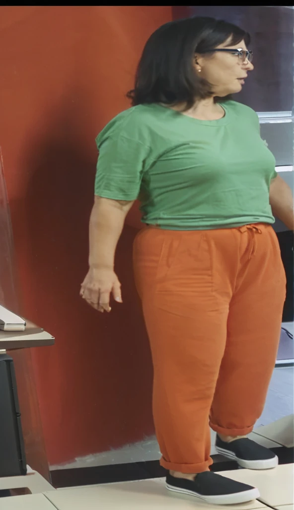 there is a woman standing in front of a computer screen, red shirt brown pants, wearing an orange t-shirt, wearing an orange t shirt, wearing pants and a t-shirt, middle shot waist up, wearing pants, wearing an orange jumpsuit, wearing orange prison jumpsuit, orange fluffy belly, vibrant but dreary orange, hand on hips, large pants