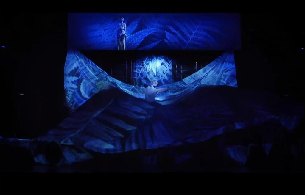 Stage scene concept、Stage lighting、Flowing curtain、arafed image of woman in skirt on stage, Projection design and installation, projection mapping, The back of the scene design element, Holographic projection, Hologram, With screens and silk, 巨大的Hologram, 空灵Hologram中心, footage of a theater stage, Alana Fletcher