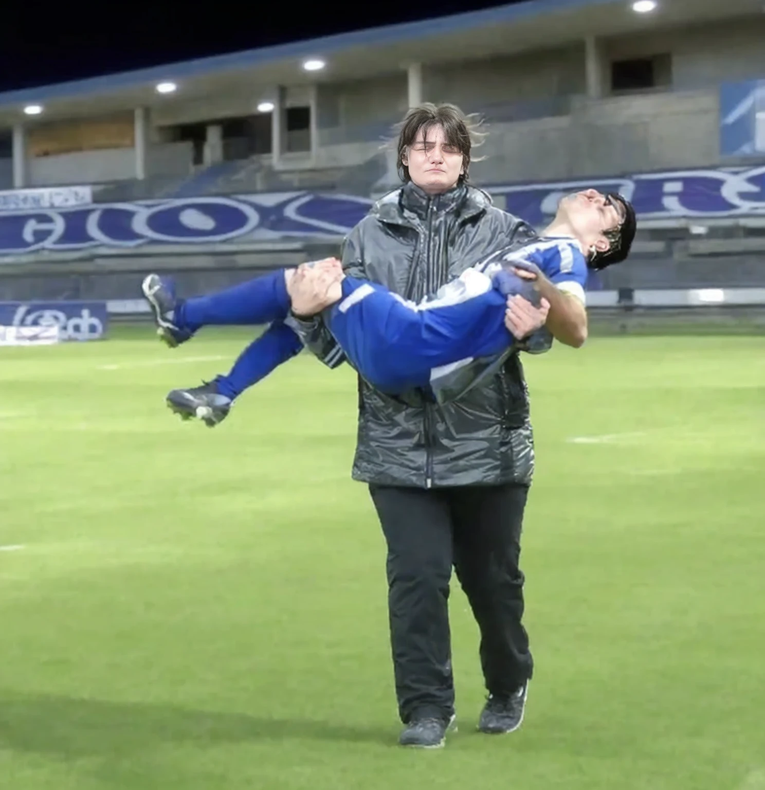 soccer action pose, cradle-carry-pose, Erste help in einem Sportstadion, affection pose, lecherous action pose, dramatic action pose, theatralic pose, There is an attractive long-haired woman, a wounded athlete in her arms, There is a beautiful long-haired woman in a shiny black outfit, who carries a short-haired young footballer in her arms, a long-haired beautiful woman in a high-gloss black down coat, a long-haired woman in a shiny black coat, A woman wears a short-haired man, Wearing a matte cotton sports outfit, a weak man in matte cotton sports shorts is consciousless and needs to be carried, A short-haired man with closed eyes is carried by a long-haired woman, a woman looks very scared and terrified, a consciousless man with closed eyes is suffering very much and has a very painful face, photoshot, photoshotshooting, photographed , accident, help, aid, Erste help, pity
