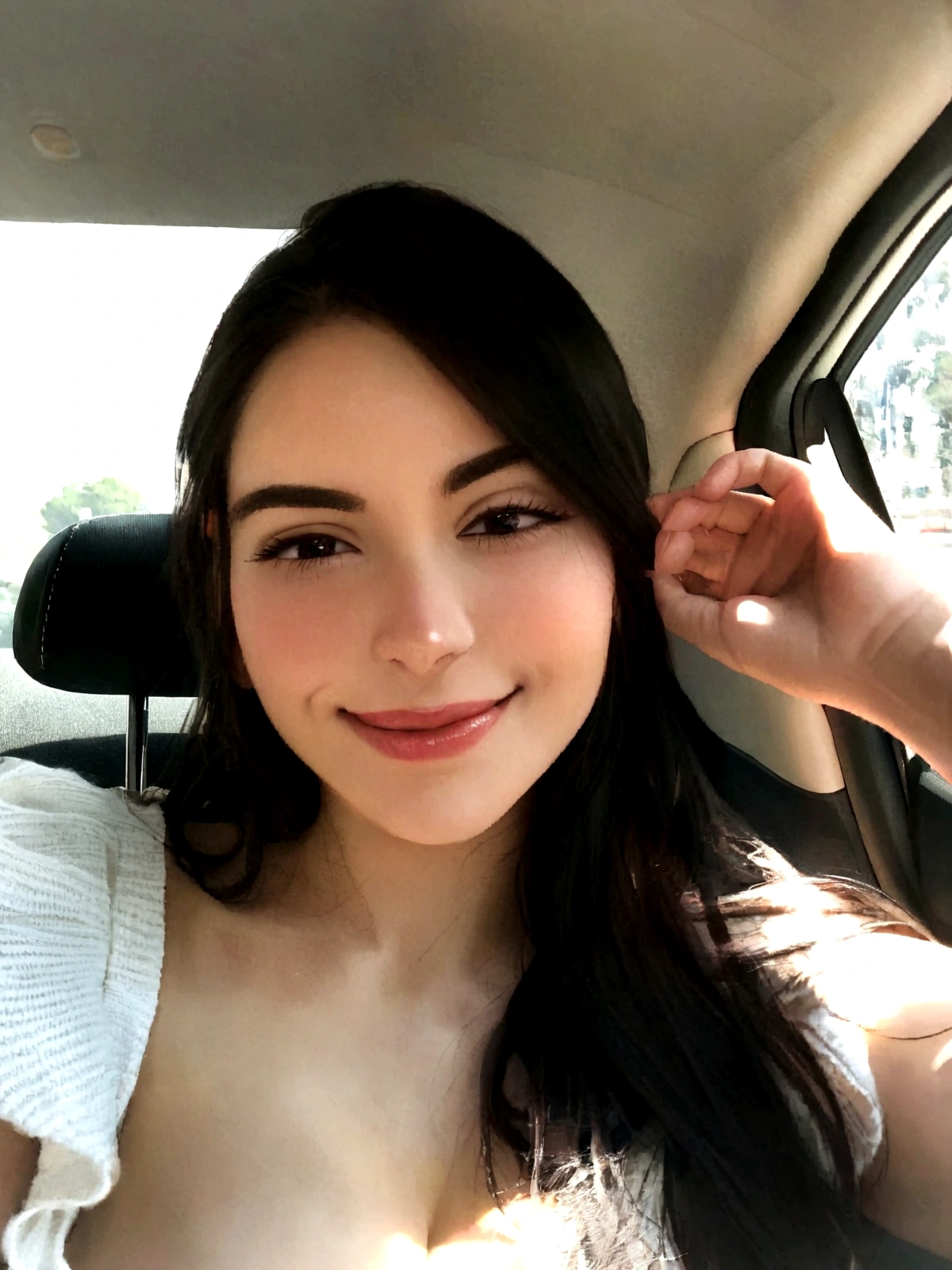 Woman with dark hair, fair skin, inside a car, small eyes, looking happy and serene