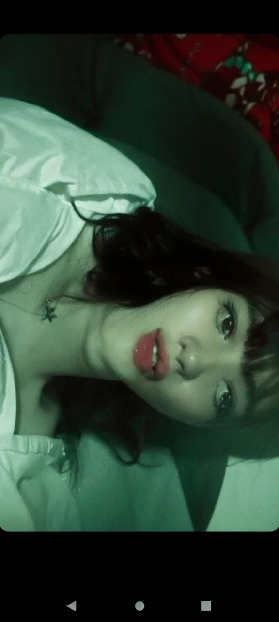 A white girl with black hair who wears bangs, her hair is long and her bangs go to her eyebrows, taking a selfie, she is wearing a star necklace, the photo is supposed to be gray and black, SHE IS SERIOUS, the image has to be as realistic as possible , She is Brazilian , shes alone, she is 17 years old, your eyes are delicate, she is wearing a little eyeliner, your nose is beautiful and your mouth is pink 