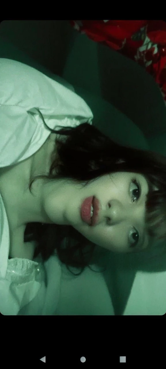 A white girl with black hair who wears bangs, her hair is long and her bangs go to her eyebrows, taking a selfie, she is wearing a star necklace, the photo is supposed to be gray and black, SHE IS SERIOUS, the image has to be as realistic as possible , She is Brazilian , shes alone, she is 17 years old, your eyes are delicate, she is wearing a little eyeliner, your nose is beautiful and your mouth is pink