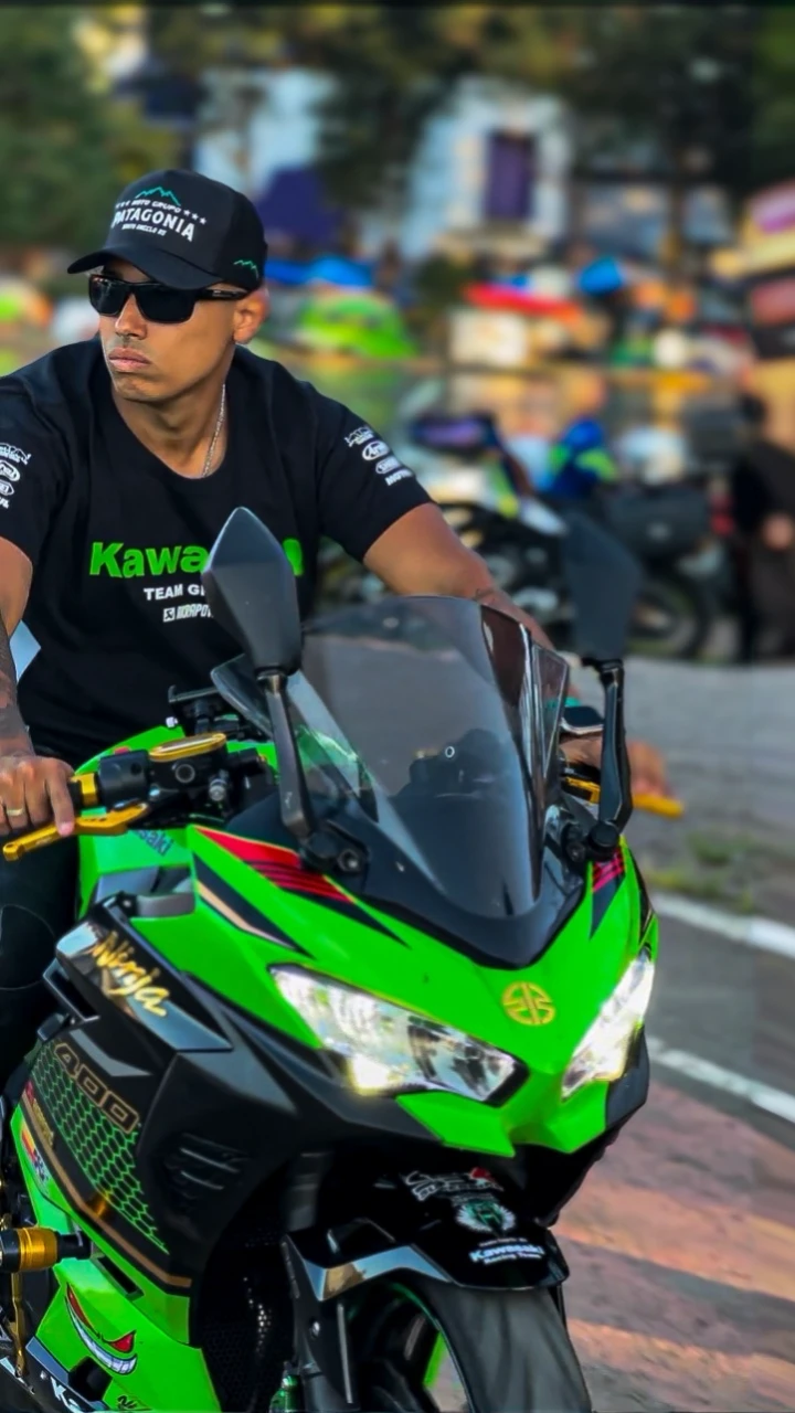 Man riding a Kawasaki ninja motorcycle at a motorcycle event 
