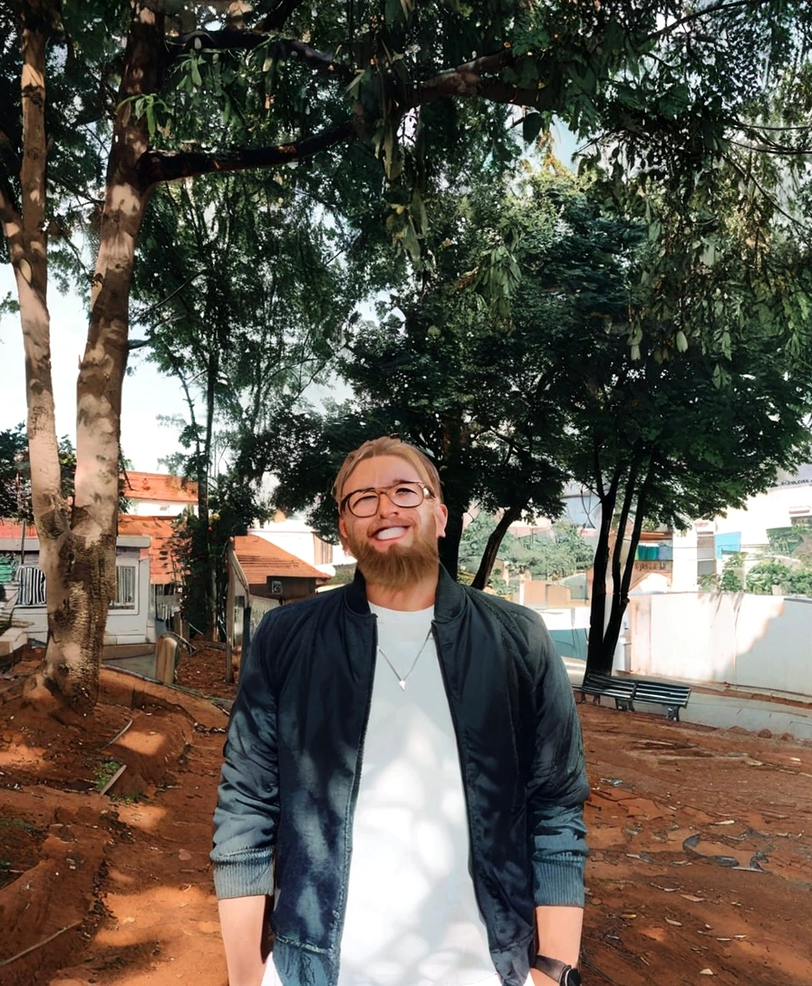 man with glasses, cape and blond beard smiling with hospital background