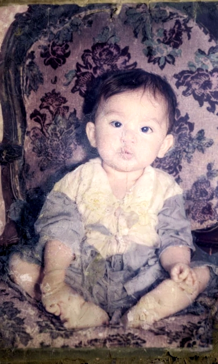 arafed photograph of a baby sitting on a chair with a flowered background, restored, best quality, highly detailed, baby boy