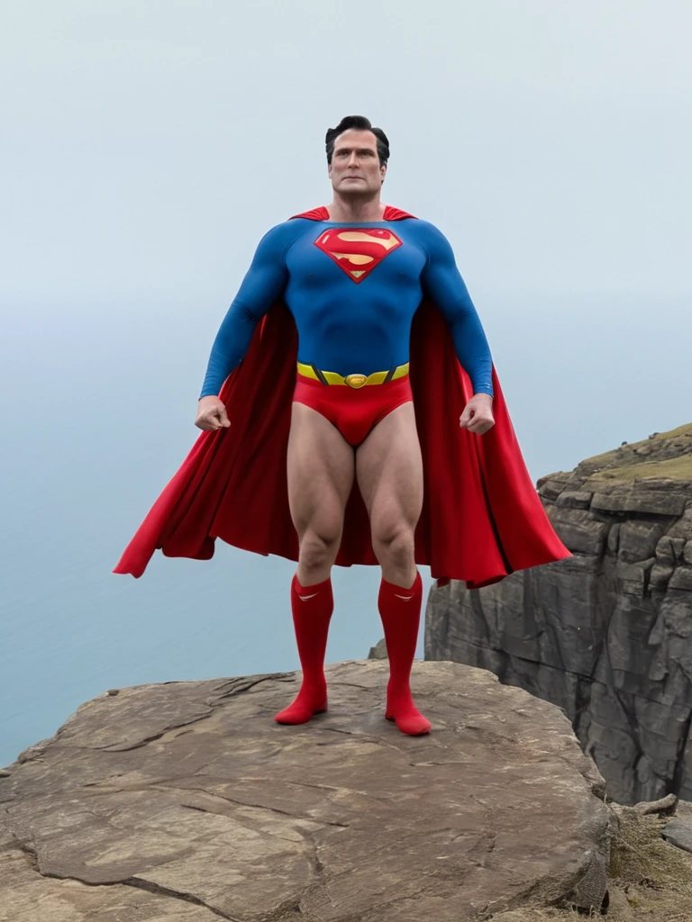 Cold, cloudy sky, middle-aged Superman, broad shoulders, protruding chest, thick neck, arms and thighs that have gained fat, no abdominal muscles, dull colored costume, Superman mark spread out to the sides, small red briefs bulging, cape fluttering in the strong wind, standing on a cliff