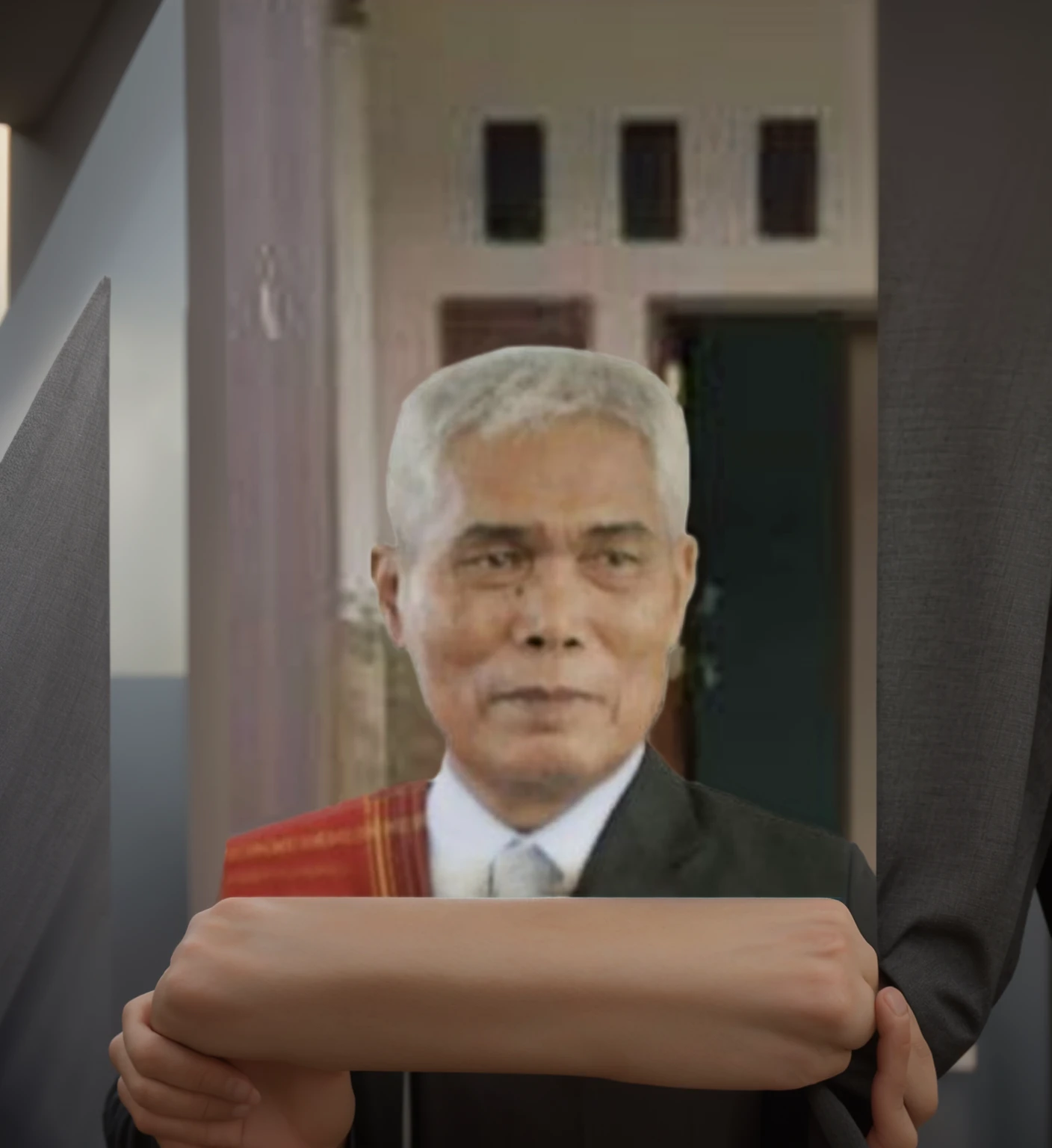 man wearing a black suit and a cloth over his shoulders, in front of the house