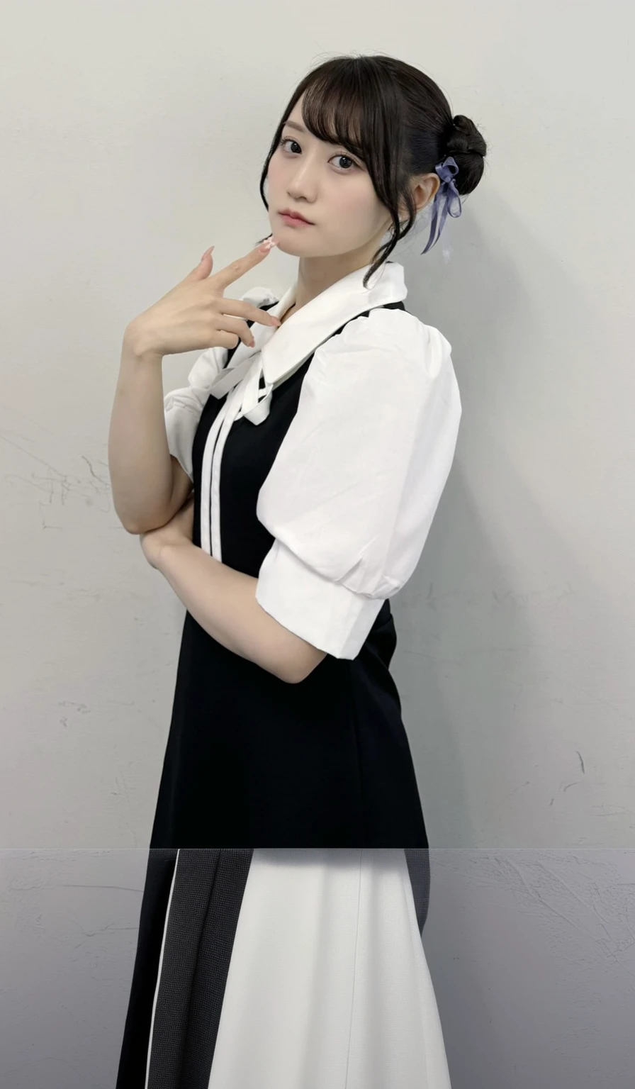 A woman in a black and white dress poses for a photo,