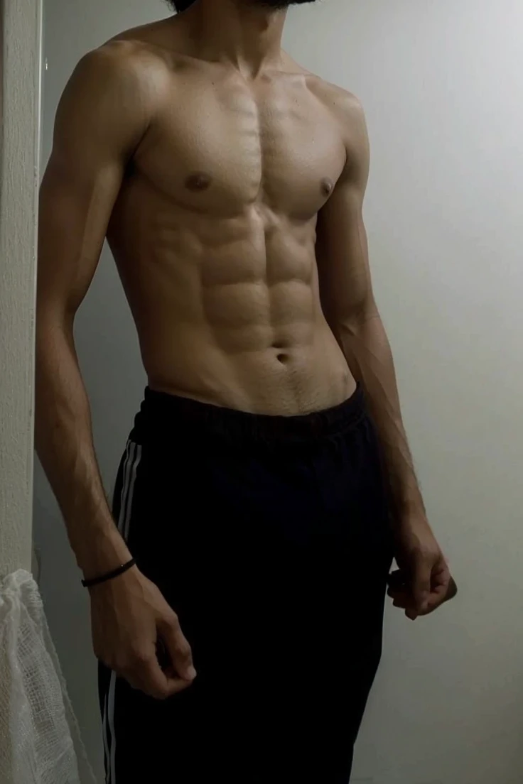 selfie of an uruguayan male with a muscular body, curly short black hair, dark brown eyes, shirtless. common teenager bedroom background. blurry low quality mirror selfie.