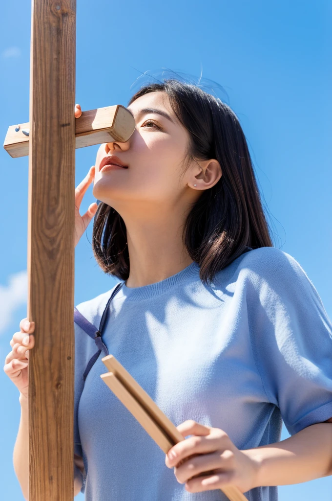 Woman in her 20s holding a wooden box against the blue sky