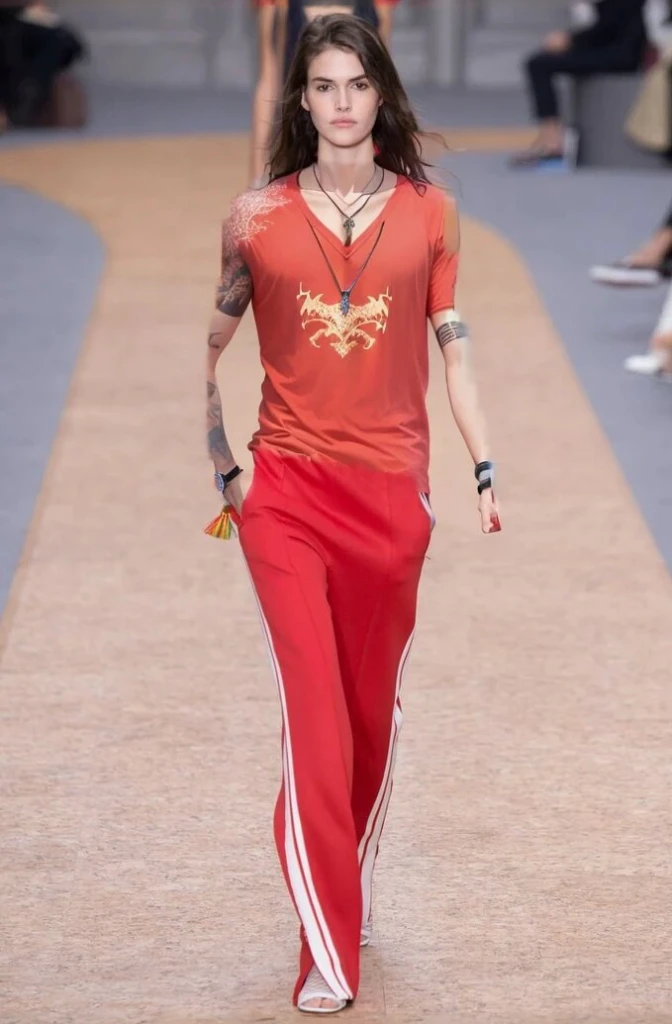 A woman wearing a red top and red pants walks on the catwalk, cai xukun, Inspired by Zou Yigui, gucci (gucci) fashion show, Inspired by Roma, Gorgeous red costume, style blend of the vatican, Colorful and rich fantasy costumes, Inspired by Pu Hua, Inspired by Yao Tingmei, Wearing a track suit, Inspired by Liu Haisu
