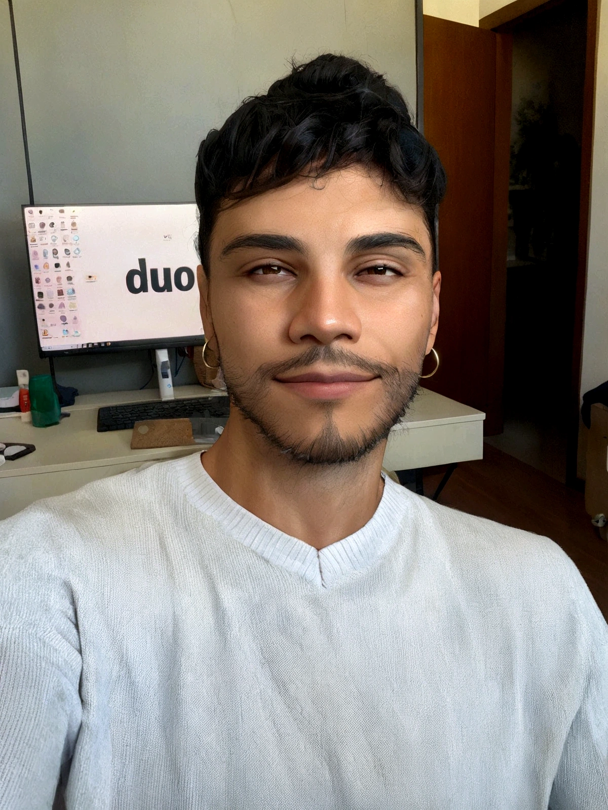 thin Hispanic man with black hair and beard, smiling, wearing small silver hoop earrings