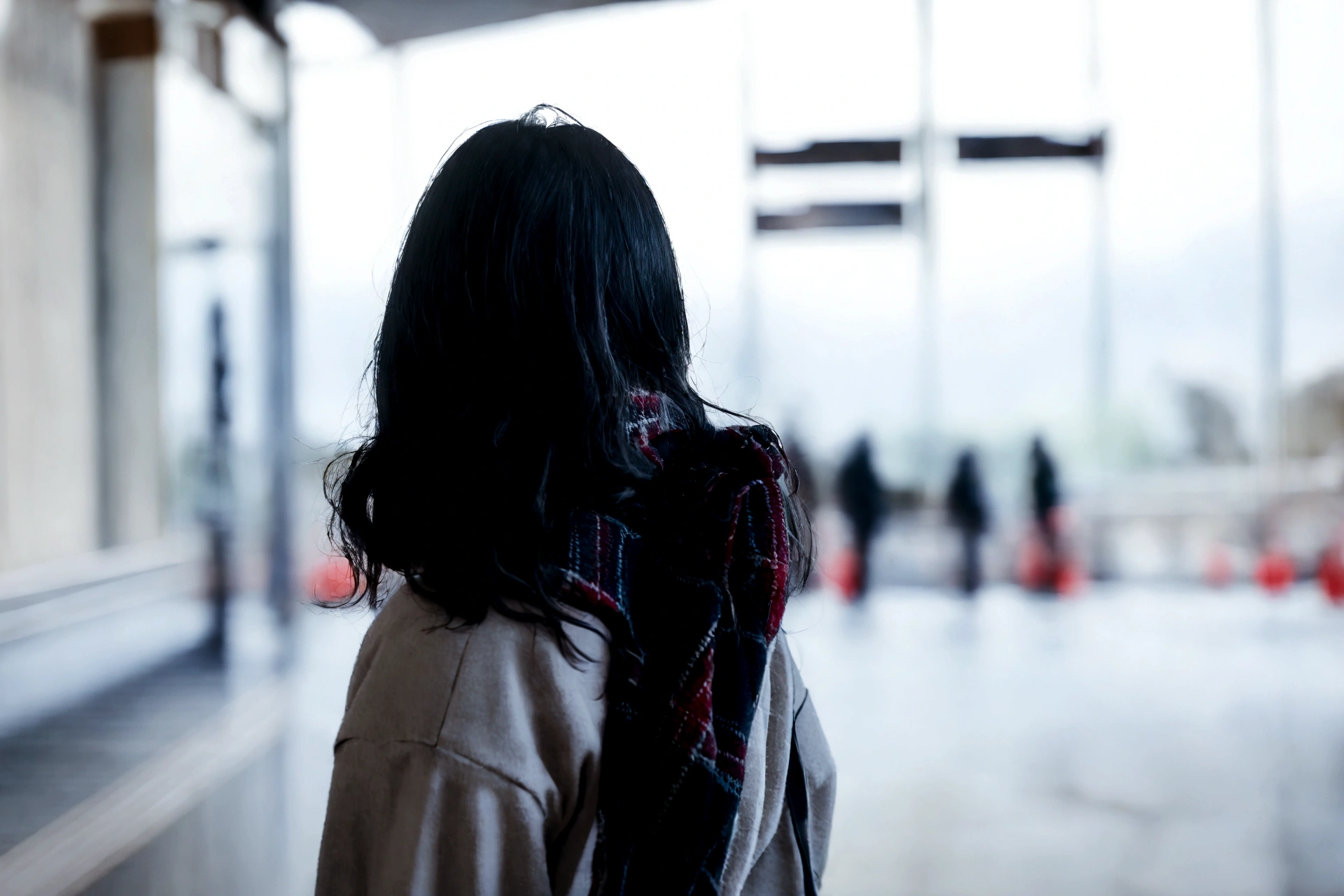 There is a woman standing in the forest, Figures in the foreground, Turning away from the camera, Turning away from the camera,A girl in the forest, Look ahead, Person standing in front of, human staring blankly ahead, Photo from the shoulders up, In the distance, Close-up shot from behind