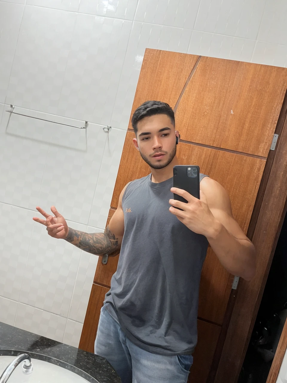 a beautiful 25 year old gamer boy (Deivid Burch:0.5), (((skin texture:1))), ((natural skin)), (black hair), (pale skin), strong body, (high detail low cut white tank top with logo), (shorts jeans), sitting at PlayStation, gaming, headset, widescreen, (masterpiece) (perfect proportion)(realistic photo)(best quality) (detailed) shot on a Canon EOS R5, 50mm lens, F/2.8, HDR, (8k) (wallpaper) (cinematic lighting) (gamer lighting) (sharp focus) (intricate), RAW photo, posing for camera, 8k uhd, dslr, high quality, film grain, shot by Arny Freytag