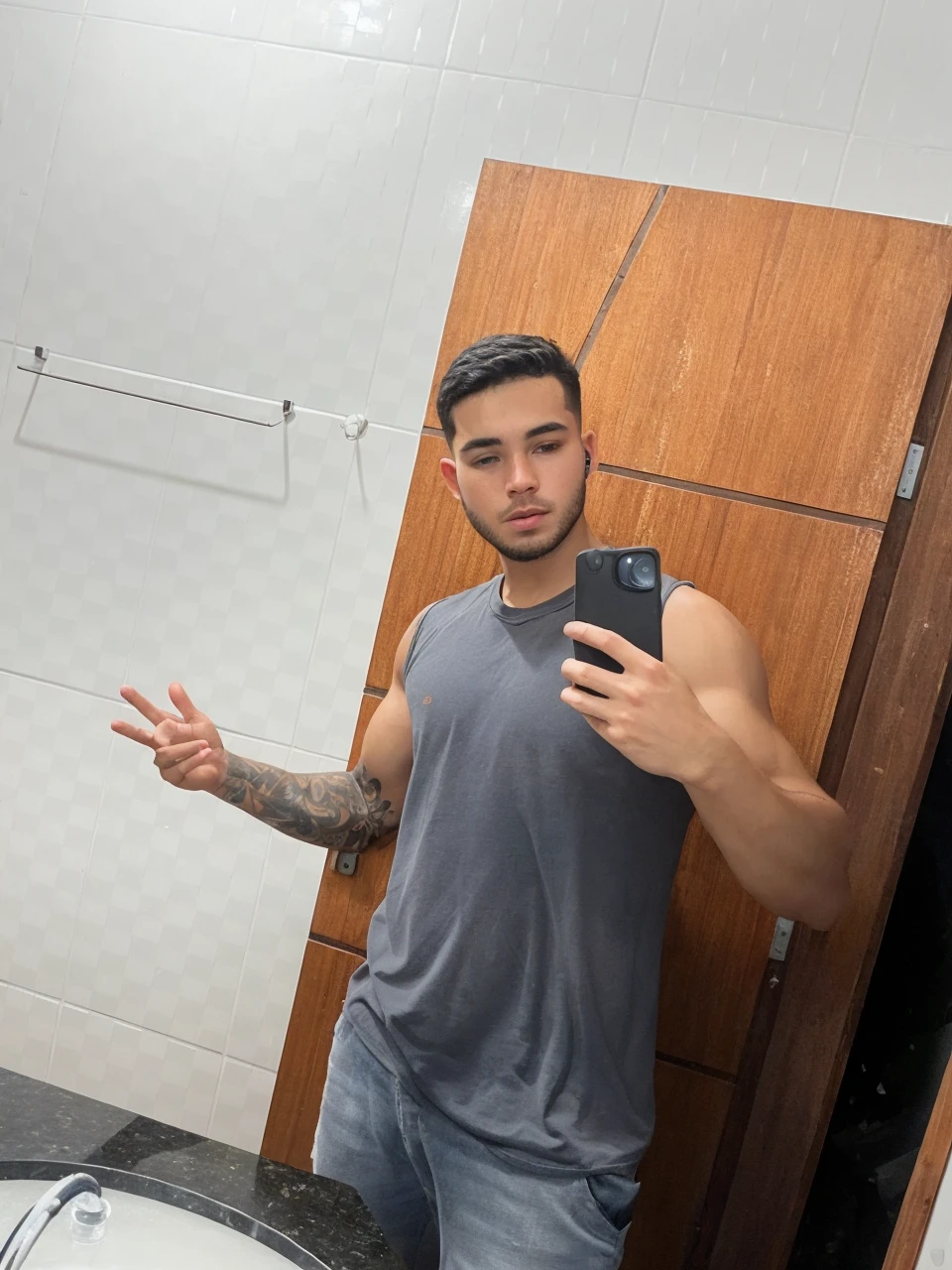 a beautiful 25 year old gamer boy (Deivid Burch:0.5), (((skin texture:1))), ((natural skin)), (black hair), (pale skin), strong body, (high detail low cut white tank top with logo), (shorts jeans), sitting at PlayStation, gaming, headset, widescreen, (masterpiece) (perfect proportion)(realistic photo)(best quality) (detailed) shot on a Canon EOS R5, 50mm lens, F/2.8, HDR, (8k) (wallpaper) (cinematic lighting) (gamer lighting) (sharp focus) (intricate), RAW photo, posing for camera, 8k uhd, dslr, high quality, film grain, shot by Arny Freytag
