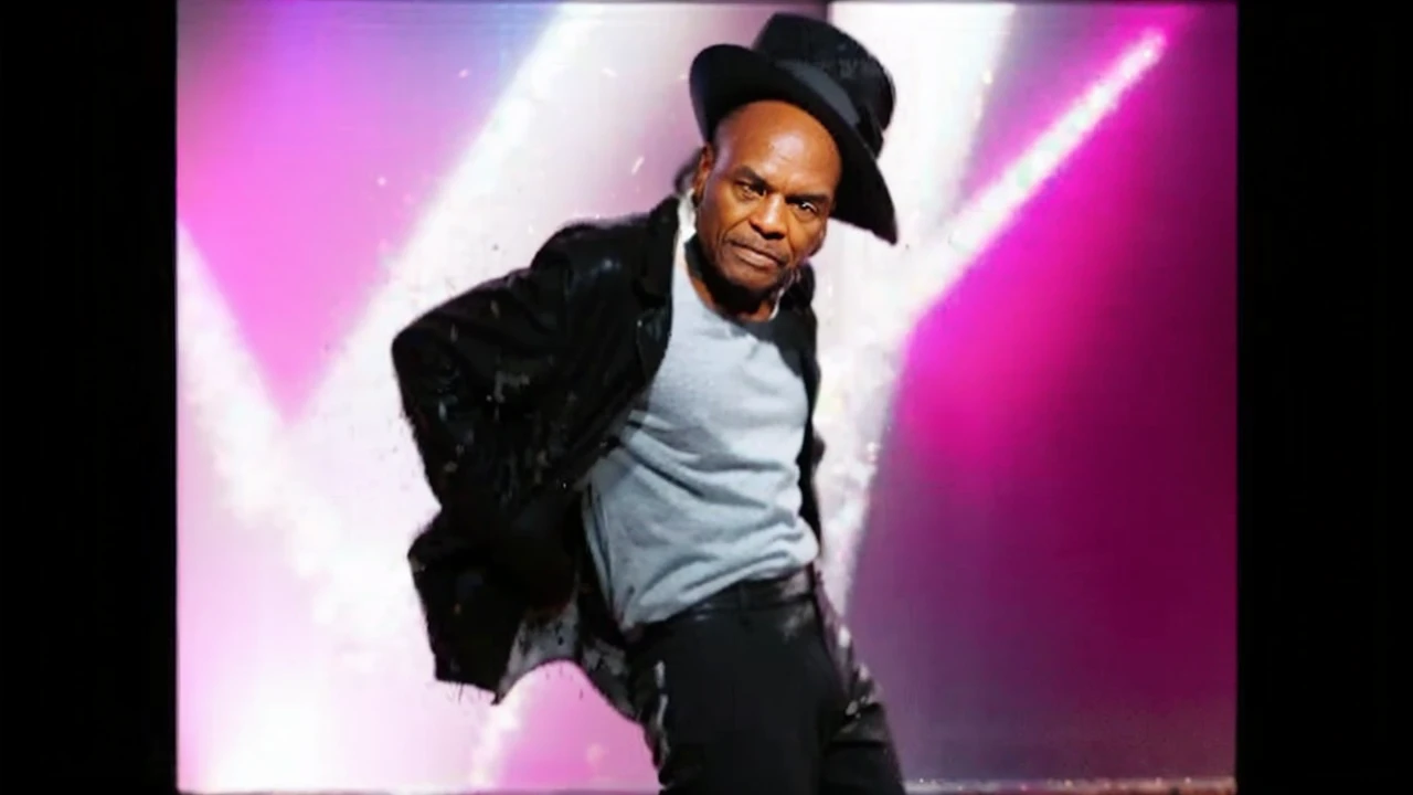 A Old Black man with receding hair line looking to left and wearing a Black Glitter jacket and wearing a Black pants with line and wearing a Black hat And Dancing on Floor