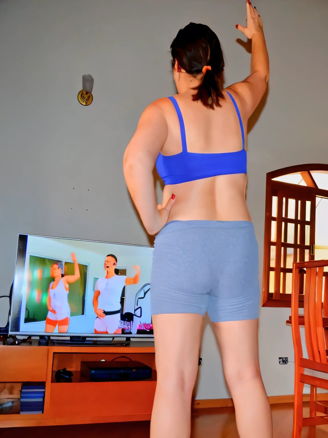 there is a woman in a blue top and blue shorts playing wii, cottagecore!! fitness body, sport bra and shorts, in shape, toned derriere, dancing in the background, sport bra and dark blue shorts, workout, back - shot, working out, rear-shot, shapely derriere, in an action pose, other women dancing behind