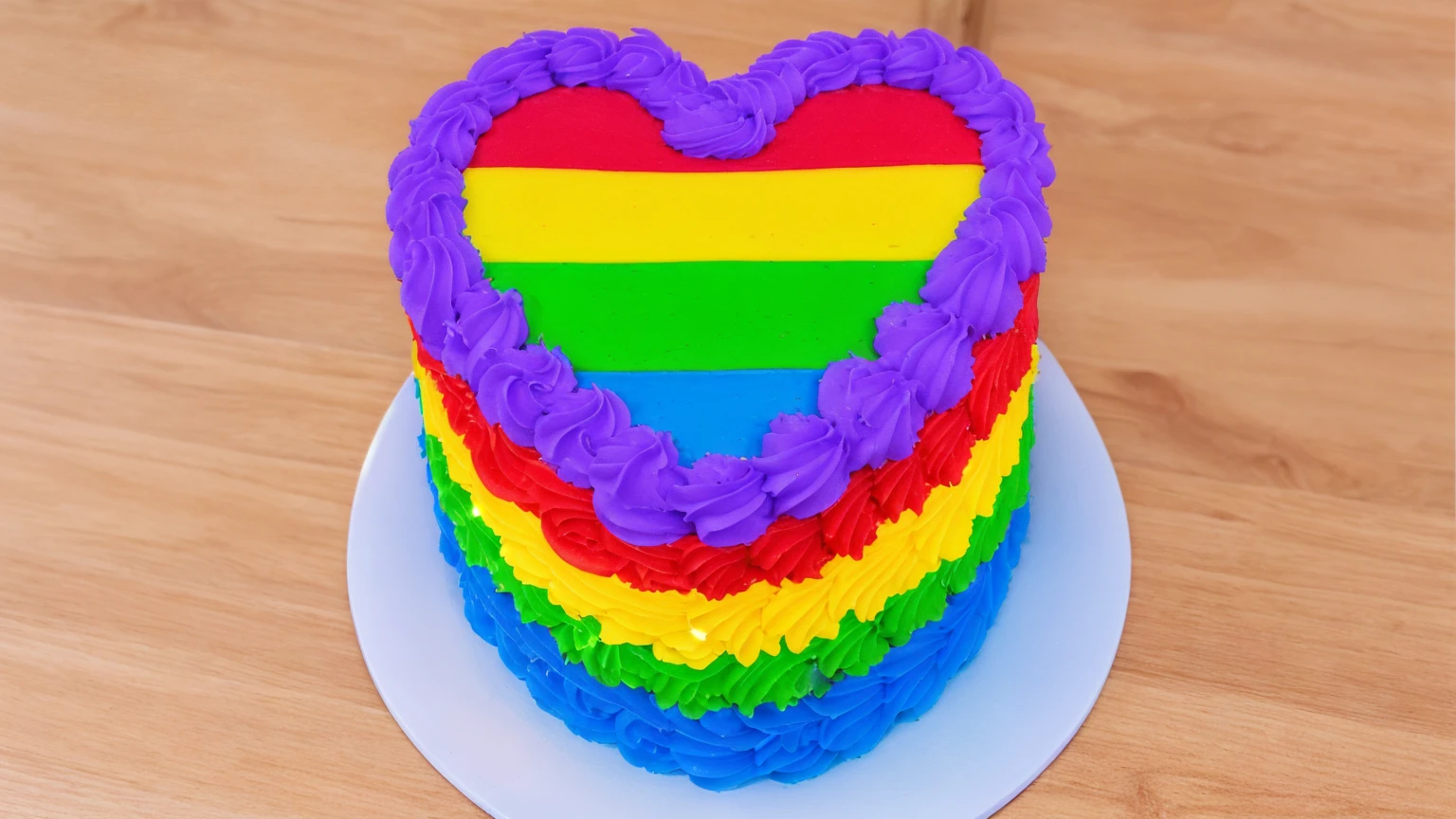 on a wooden table, there is a white plate with a heart cake , rainbow cream heart cake ( star shaped) , multi-colored heart on top, decorated with purple cream, cream with highlights, view from above,  Beautiful light from the window, beautiful lighting, bright announcement, Multiple light sources, Realistic style, realistic textures, high quality, high detail, detailed textures, ultra 4k hd, macro photography