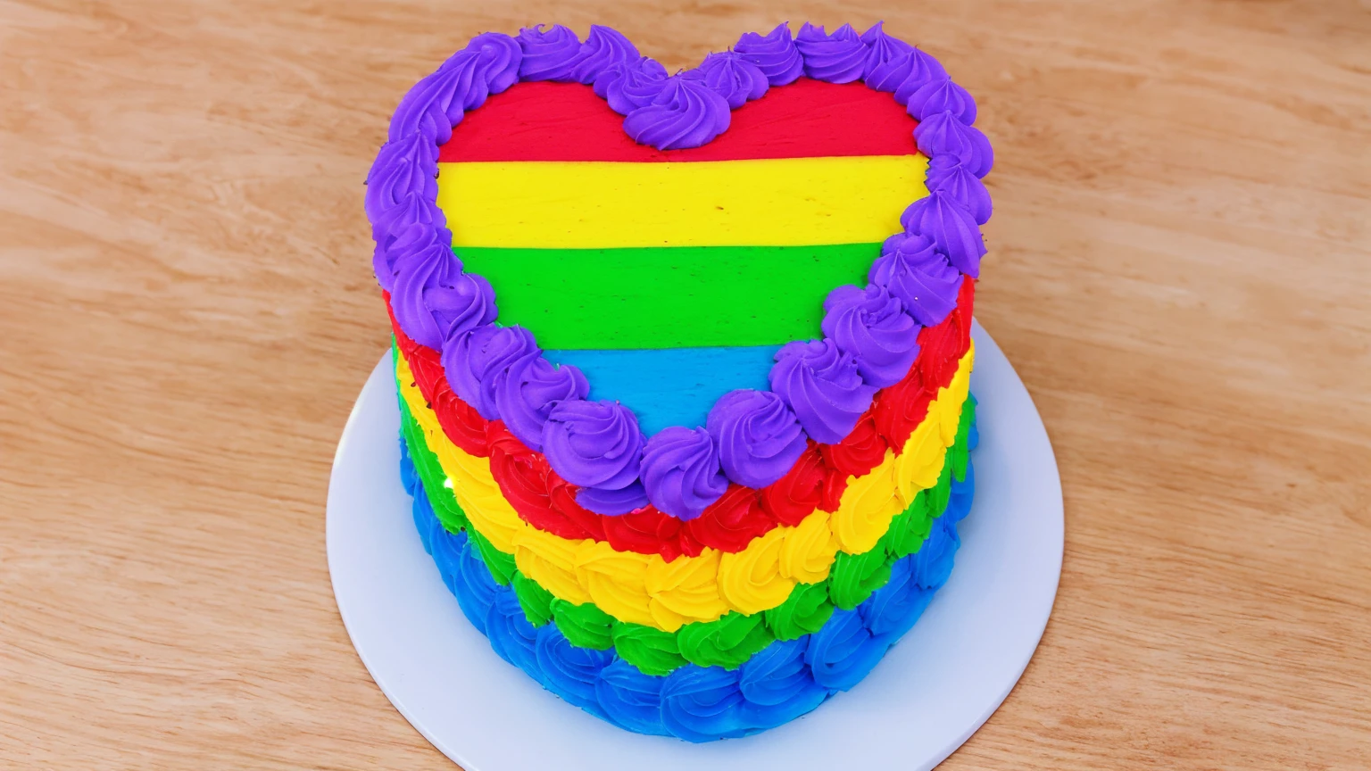 on a wooden table, there is a white plate with a heart cake , rainbow cream heart cake ( star shaped) , multi-colored heart on top, decorated with purple cream, cream with highlights, view from above, Beautiful light from the window, beautiful lighting, bright announcement, Multiple light sources, Realistic style, realistic textures, high quality, high detail, detailed textures, ultra 4k hd, macro photography
