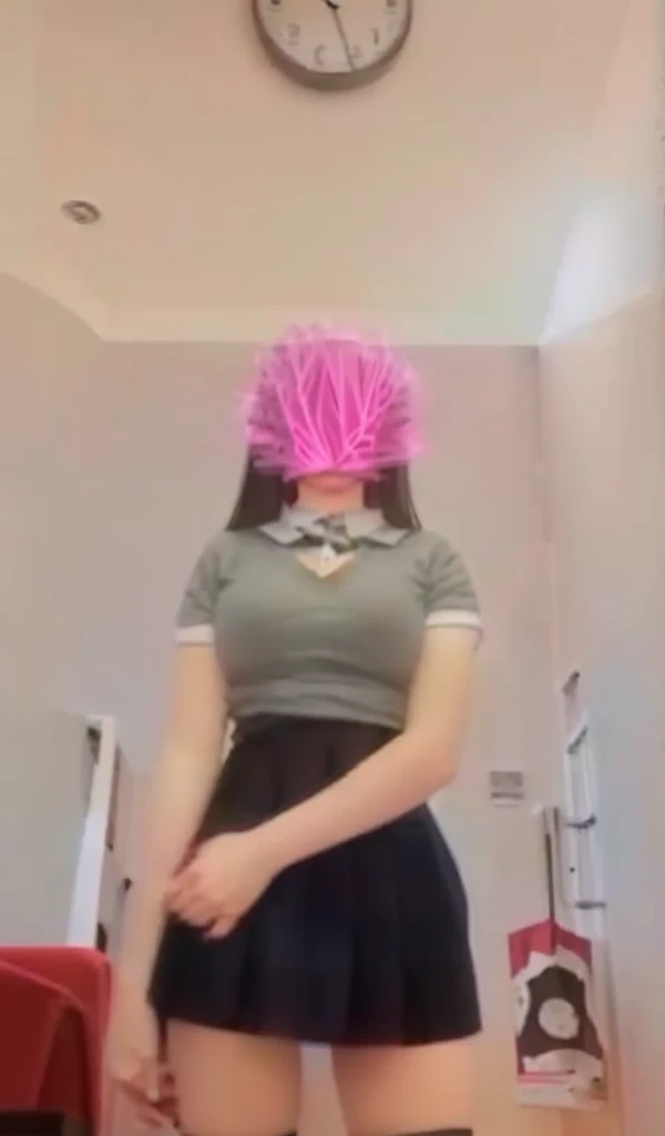 A 13-year-old woman wears a short skirt and black stockings and has A-cup breasts.
