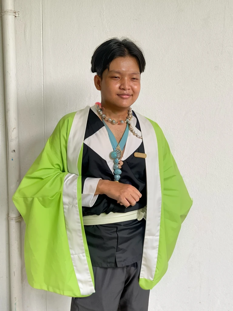 Gyomei wears a traditional Japanese kimono with a long, flowing white robe.
Over the kimono, he dons a sleeveless haori (a traditional Japanese jacket) that is primarily dark green with a geometric pattern.
Belt (Obi):
He wears a wide, dark belt (obi) that secures his kimono and haori.
Beads and Rosary:
One of his most distinctive accessories is a large rosary necklace made of prayer beads, which he often holds in his hands.
Footwear:
Gyomei wears traditional Japanese sandals (zori) with white tabi socks.