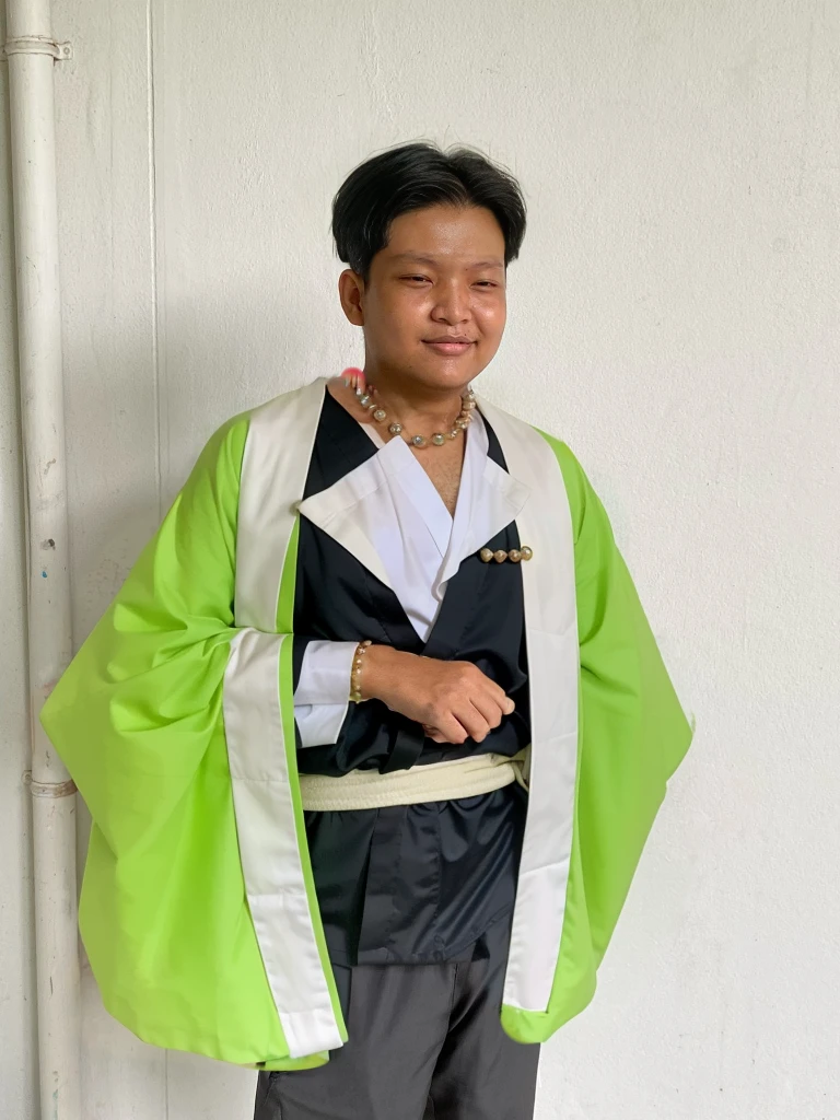 Gyomei wears a traditional Japanese kimono with a long, flowing white robe.
Over the kimono, he dons a sleeveless haori (a traditional Japanese jacket) that is primarily dark green with a geometric pattern.
Belt (Obi):
He wears a wide, dark belt (obi) that secures his kimono and haori.
Beads and Rosary:
One of his most distinctive accessories is a large rosary necklace made of prayer beads, which he often holds in his hands.
Footwear:
Gyomei wears traditional Japanese sandals (zori) with white tabi socks.
