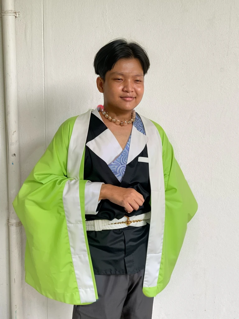 Gyomei wears a traditional Japanese kimono with a long, flowing white robe.
Over the kimono, he dons a sleeveless haori (a traditional Japanese jacket) that is primarily dark green with a geometric pattern.
Belt (Obi):
He wears a wide, dark belt (obi) that secures his kimono and haori.
Beads and Rosary:
One of his most distinctive accessories is a large rosary necklace made of prayer beads, which he often holds in his hands.
Footwear:
Gyomei wears traditional Japanese sandals (zori) with white tabi socks.