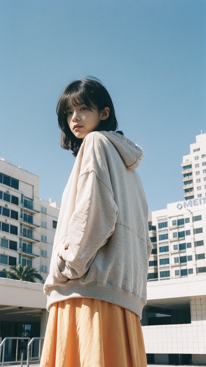 long shot portrait of cute 23 yo girl, (natural breast) ,wear ((orange color oversized hoodie)), wear ((purple tennis skirt)),looking front,Best Quality,Masterpiece,Ultra High Resolution,(Realisticity:1.4),Original Photo, 1Girl, light leak,ultra high resolution,UHD,beautiful, (black bob hair), almond eye, no makeup, in front of (80's mondrian architecture motel), (realistic:1.2), (surreal:1.3), (very detailed:1.1), ((masterpiece)),summer, blue sky, palm trees,sunny, los angles vibes,film camera, 800mm lens,style of Philip Lorca diCorcia
