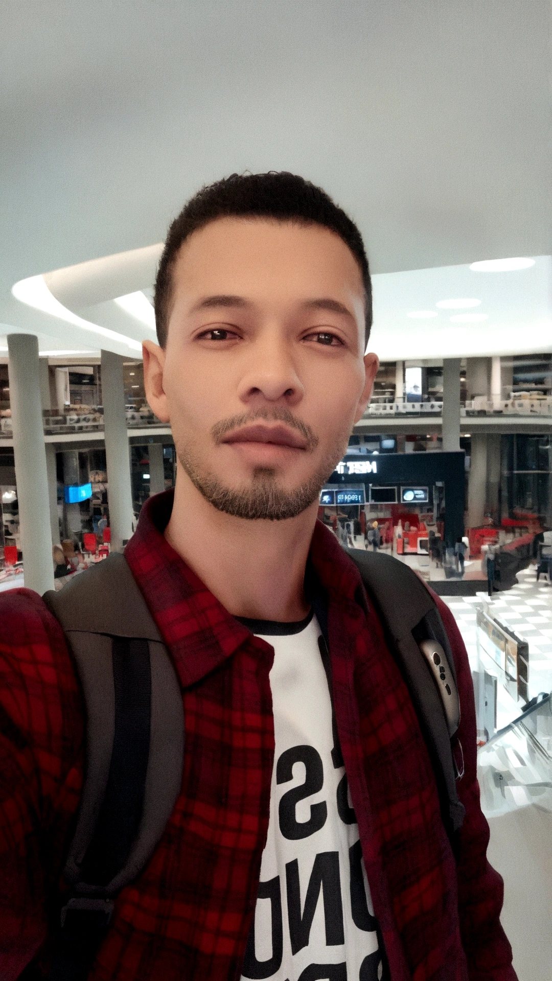 man holding an iphone 12 pro in black and in the background of the image a technological product store