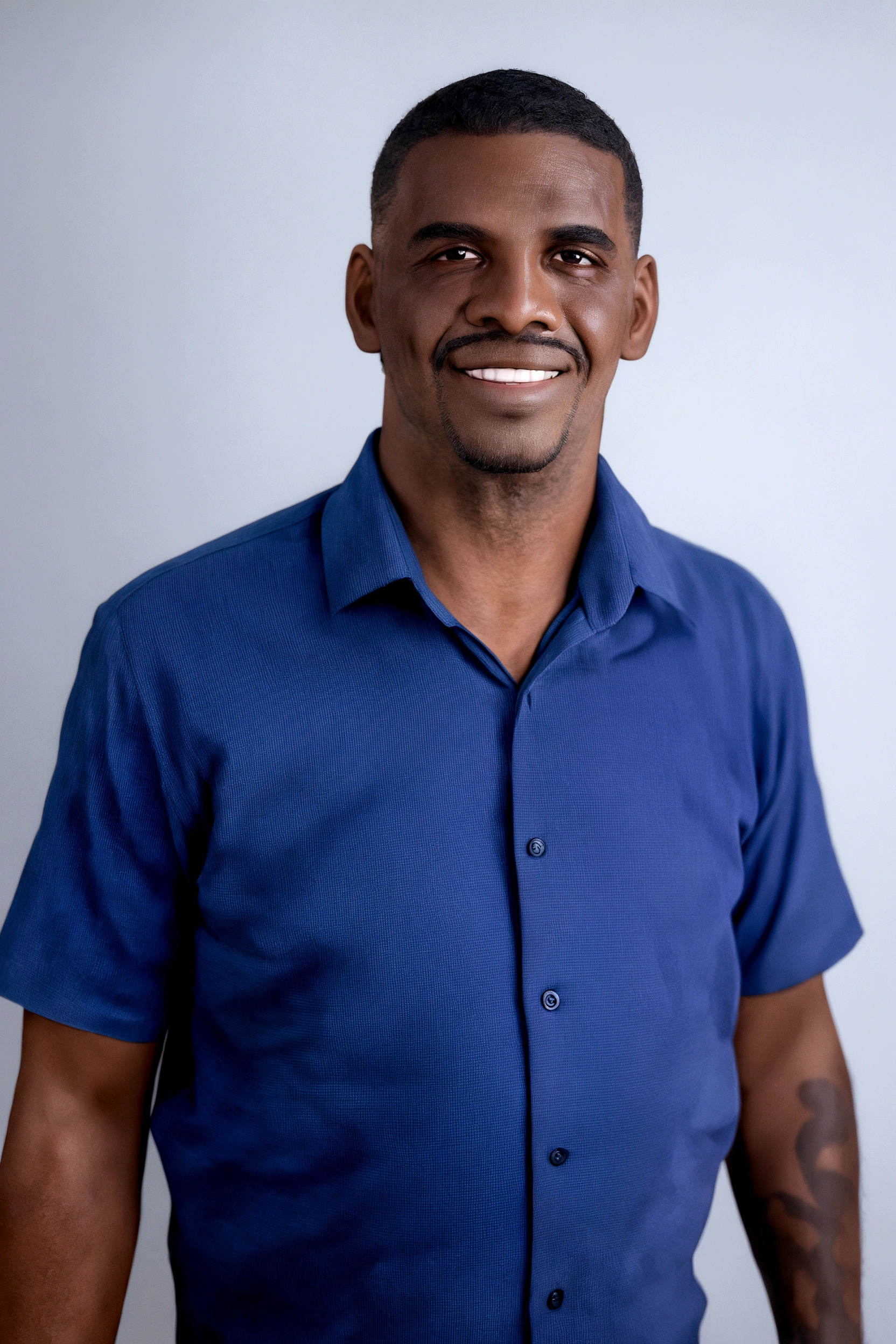 Black man, smiling, with a white background with a beard and thin mustache